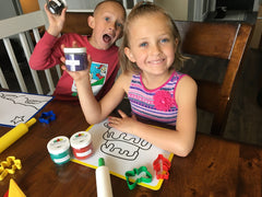 children holding up squishy dough jar